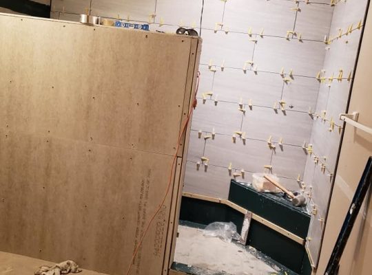 A bathroom under renovation with a shower and toilet being remodeled.