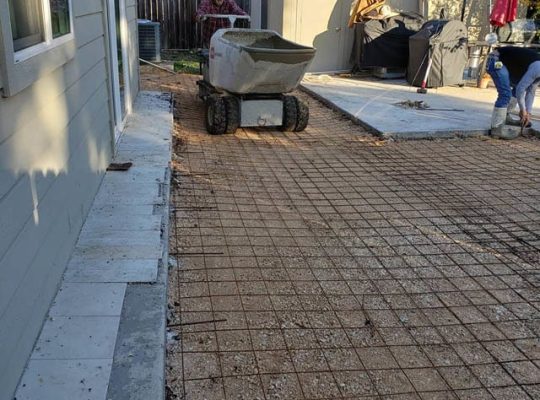 A backyard undergoing construction of a concrete patio.