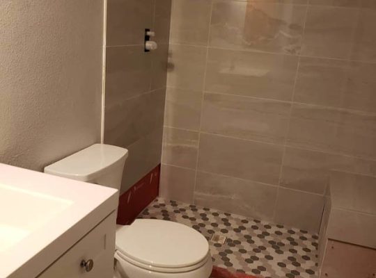 A bathroom interior with a toilet, sink, and shower.